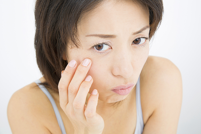 顔を触っている女性